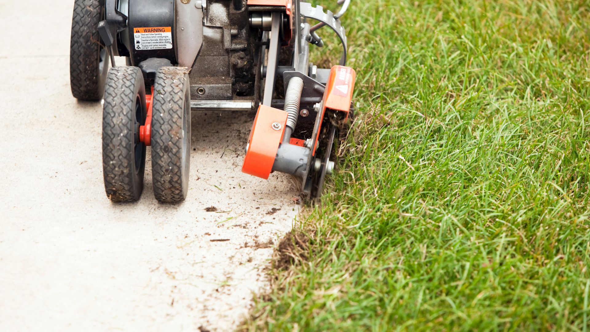 Lawn edger machine with orange and gray trim cutting grass edge