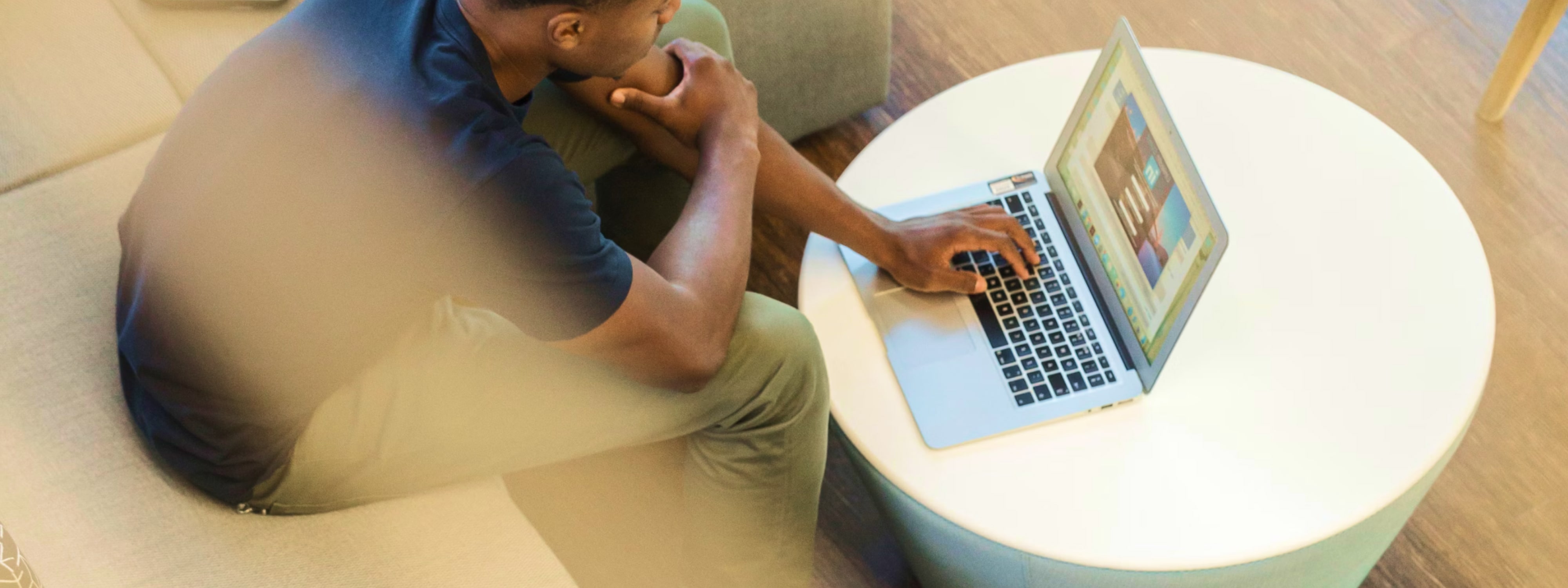 Person sitting at a white table working on a laptop